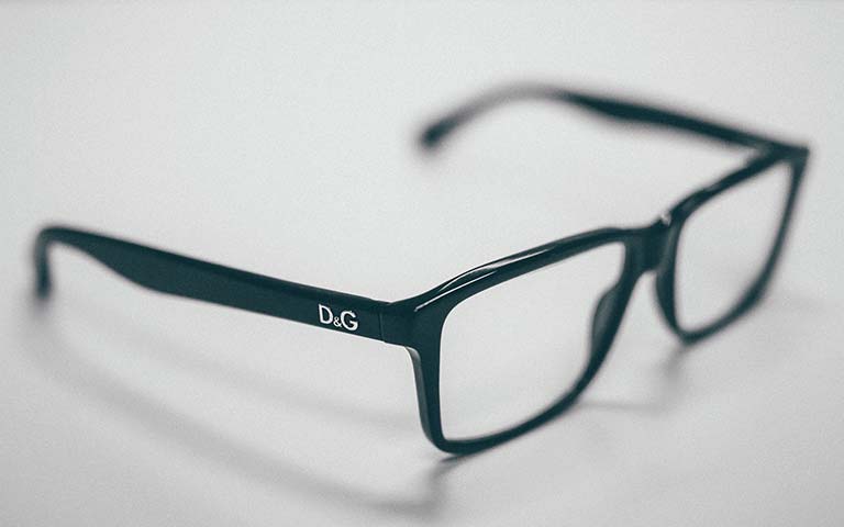 Lentes de aumento negros apoyados en una superficie blanca.